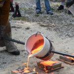Two men pouring molten iron into molds.